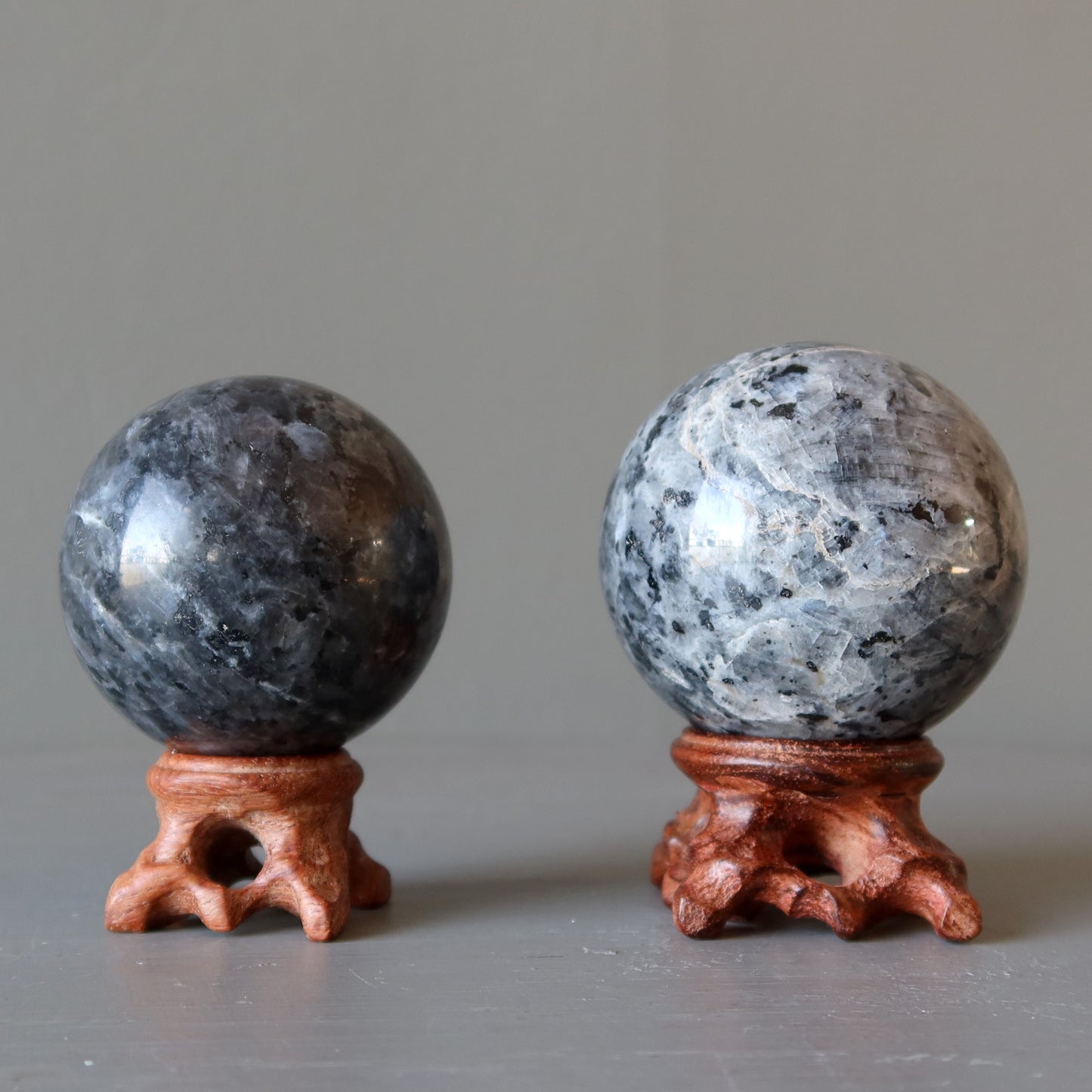 two larvikite crystal balls on wood stands