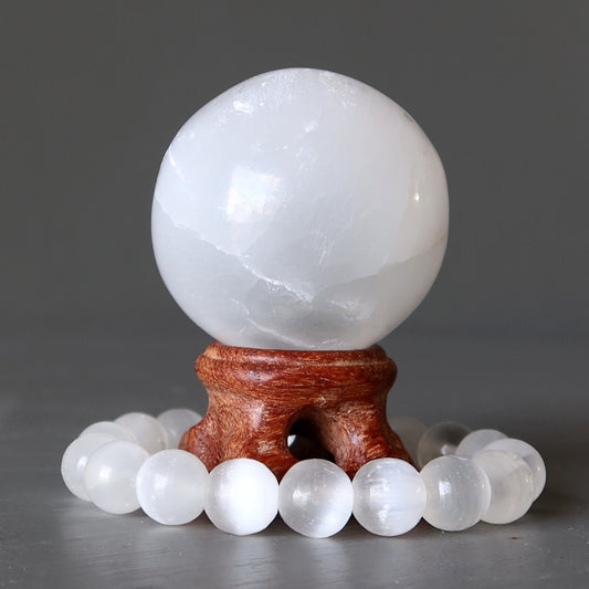 white selenite crystal ball and bracelet on wood stand